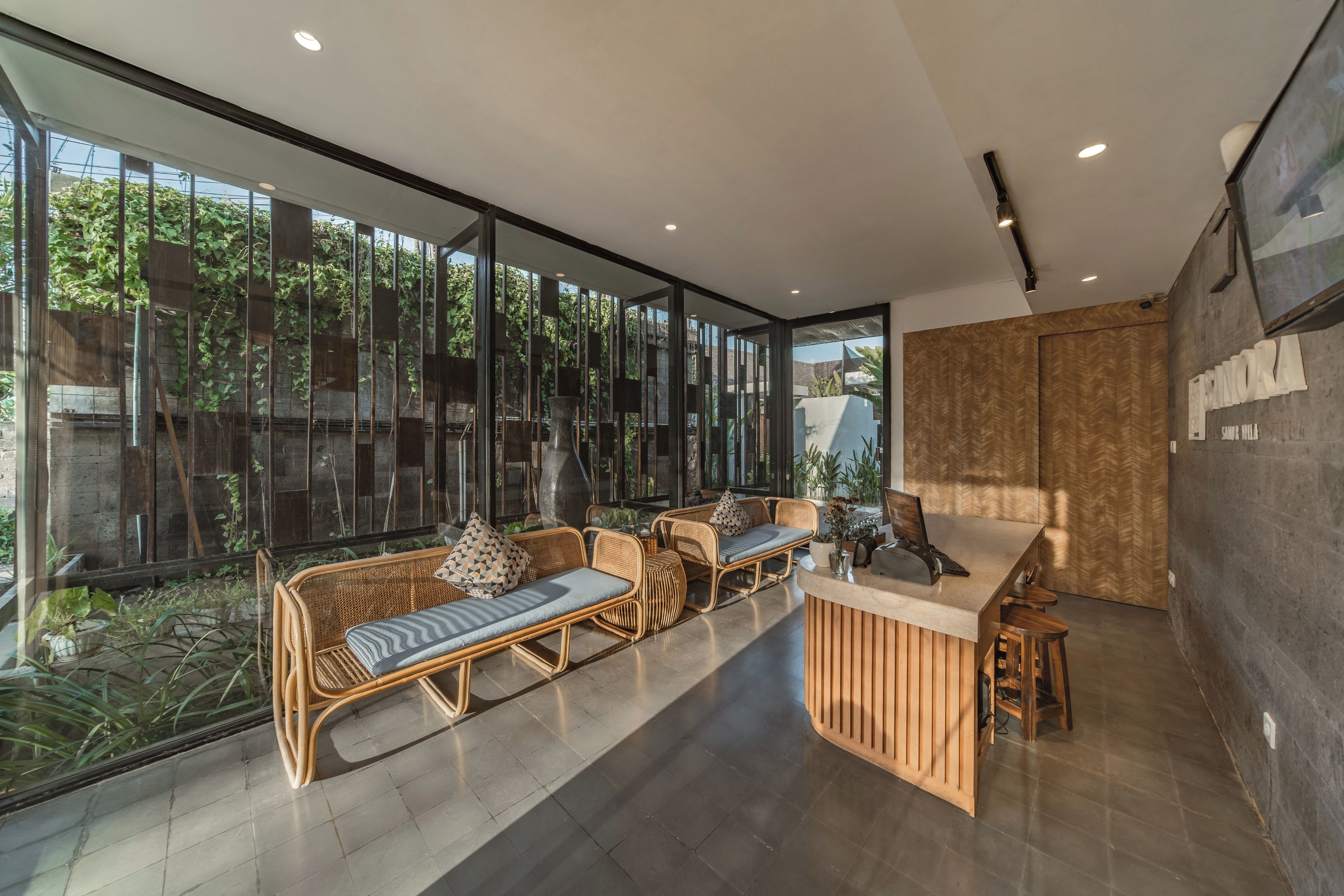 A modern interior with a glass wall, wicker furniture, and a wooden counter.