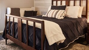 Ein Schlafzimmer mit einem hölzernen Bett, einem Deckenventilator, einer Leuchte und einem an der Wand hängenden Gemälde.
