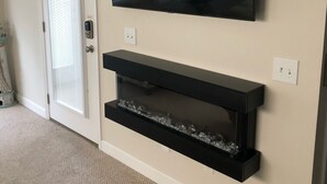A room with a television mounted on the wall above a black entertainment center.