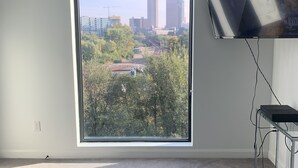 A room with a large window, a bed, a TV, and a desk. - TOP FLOOR DOWNTOWN CONDO (Columbus)