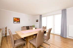 A modern dining area with a wooden table, four chairs, and a potted plant. - Ferienwohnung am Yachthafen Optional mit Bootsliegeplatz im Haus 7 - Hafenapartment 8 im (Plau am See)