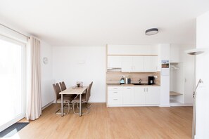 Una cocina moderna con armarios blancos, encimera de madera y comedor con mesa y sillas.