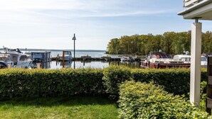 Un port de plaisance avec plusieurs bateaux amarrés, un espace verdoyant au premier plan et une étendue d’eau en arrière-plan.