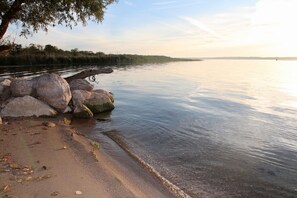 A calm river with a sandy shore and large rocks.