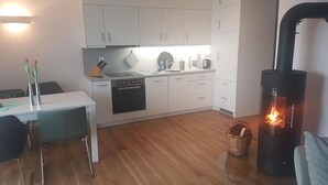 A modern kitchen with white cabinets, a stove, and a dining area with a table and chairs.