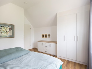 Una camera da letto con un letto, un armadio, una cassettiera e un quadro appeso al muro.