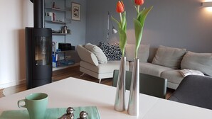 A modern living room with a sofa, a coffee table, and a fireplace. There are vases with flowers on the table.