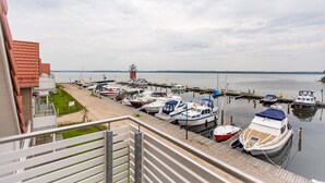 Ein Yachthafen mit vertäuten Booten, im Hintergrund ein Leuchtturm und ein Gebäude mit rotem Dach.