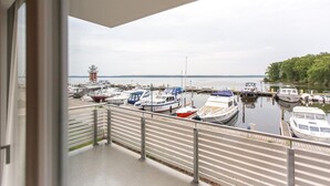 Ein Yachthafen mit verschiedenen vertäuten Booten, ein Leuchtturm im Hintergrund und Blick aufs Wasser.