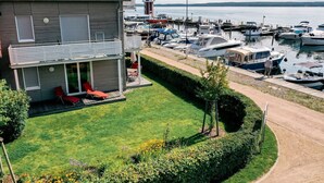 Ein modernes Haus mit Terrasse, Rasenfläche und einem Jachthafen mit Booten.