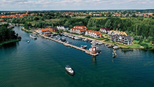Eine Stadt am Flussufer mit einem Yachthafen, Häusern und einer Kirche.