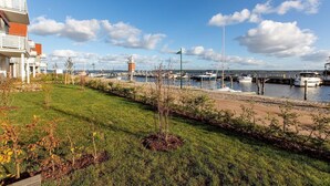A marina with boats docked, a lighthouse, and a grassy area with trees.