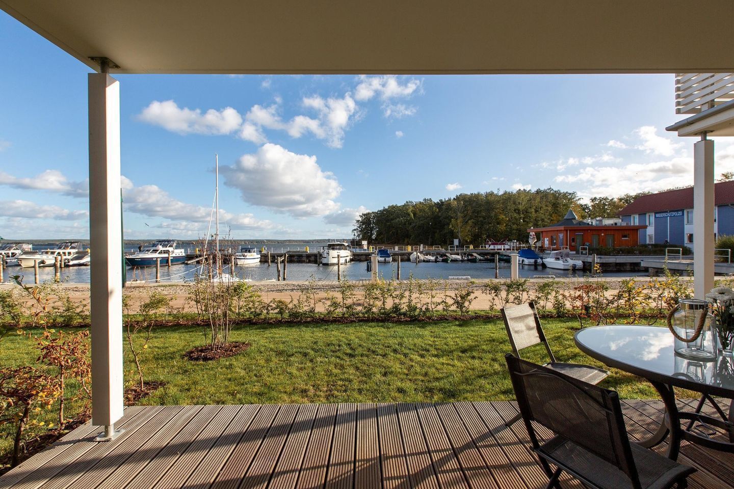 Un espace extérieur abrité avec vue sur un port de plaisance, une terrasse en gazon et une table avec des chaises.