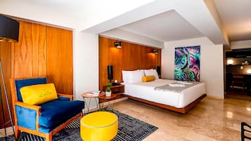Une chambre d’hôtel moderne avec un lit, un fauteuil bleu, un pouf jaune et un mur décoratif en bois.