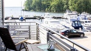 A balcony with a view of a marina, a table with a chair, and a metal railing.