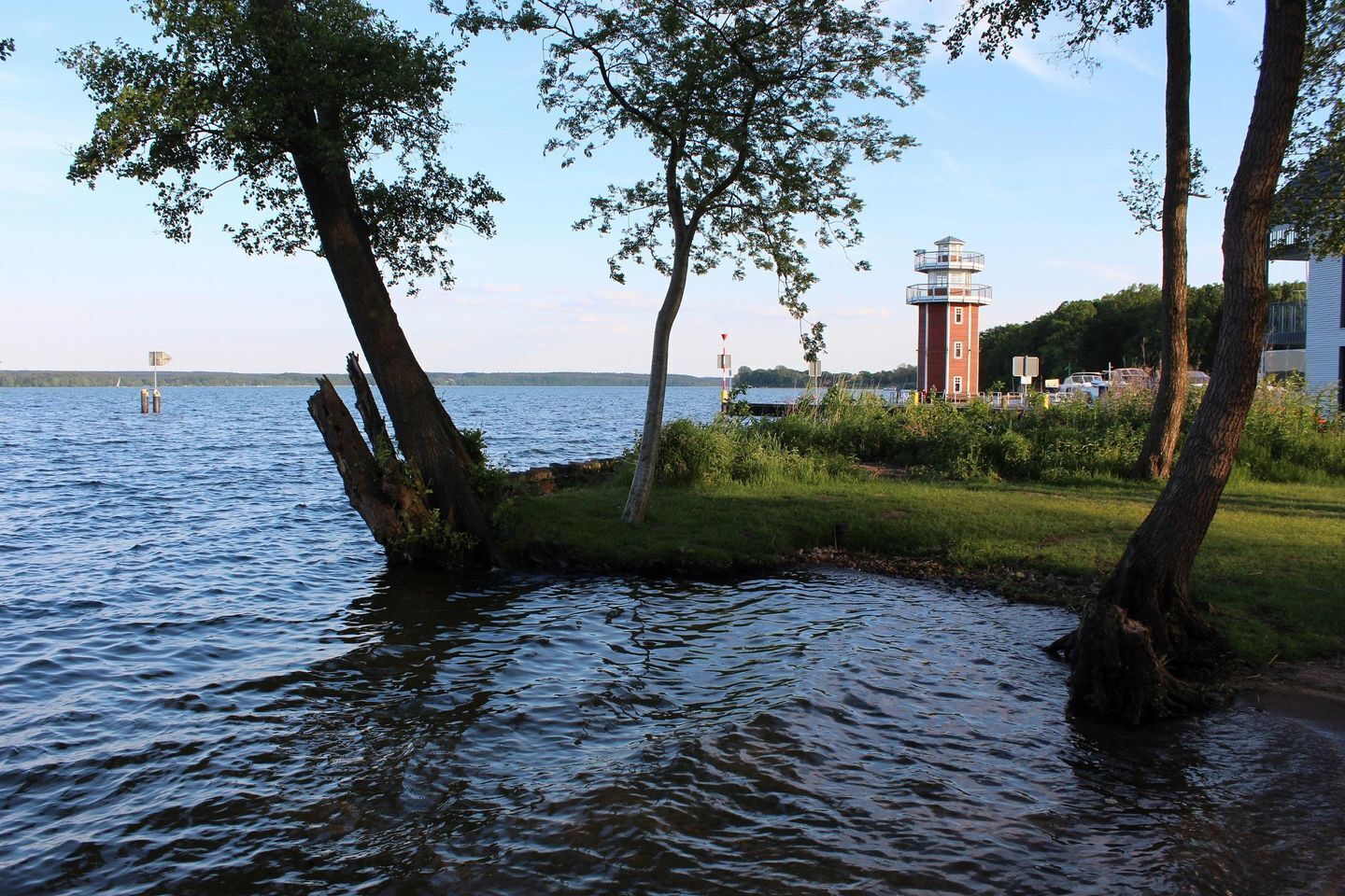 Un lago tranquillo con un faro e alberi sullo sfondo.