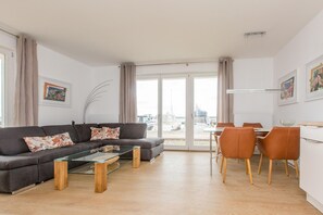 A modern living room with a sofa, coffee table, and dining area with chairs.