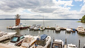 A marina with various boats docked, a lighthouse, and a calm water body under a partly cloudy sky. - Corner apartment with 2 terraces with parking at the house, dog allowed P7 A5 - 2 (Plau am See)