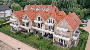 Un immeuble résidentiel à plusieurs étages, doté d’un toit rouge, de nombreux balcons et d’une pelouse bien entretenue.