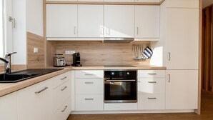 Une cuisine moderne avec des meubles blancs, un four en acier inoxydable et un plan de travail en bois.