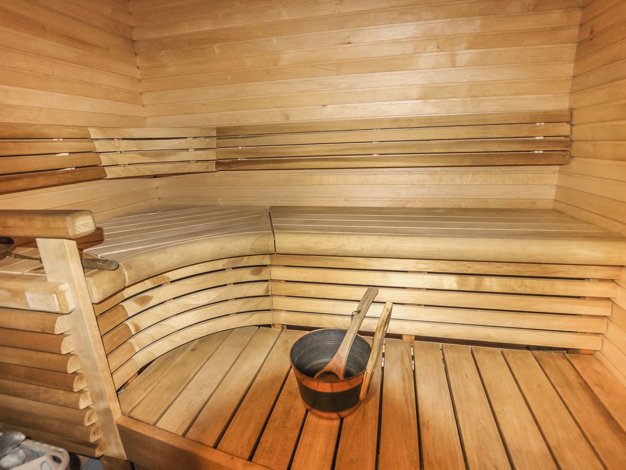 A sauna with wooden benches and a central heating element.