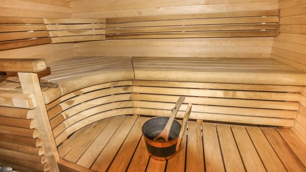 A sauna with wooden benches and a wooden bucket. - Taukotuli 4 paritalon alakerta by Interhome (Hyrynsalmi)
