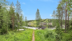 A forested area with a clear path leading to a lake, surrounded by trees and greenery. - Taukotuli 4 paritalon alakerta by Interhome (Hyrynsalmi)