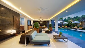 A modern living room with a poolside area, featuring a sofa, dining table, and lounge chairs. - Monolocale Resort & Spa Seminyak by Ini Vie Hospitality (Keroboken Kelod)