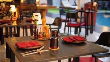 Un'ambientazione di ristorante con tavoli apparecchiati per la cena, comprensivi di piatti, posate e condimenti.