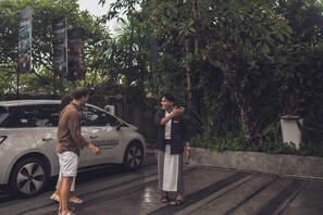 A person standing next to a white car with 'monologue' written on it, parked on a wet road with greenery in the background. - Monolocale Resort & Spa Seminyak by Ini Vie Hospitality (Keroboken Kelod)