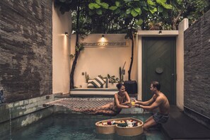 A couple relaxing by a pool with a hammock and baskets of fruits and flowers. - Monolocale Resort & Spa Seminyak by Ini Vie Hospitality (Keroboken Kelod)