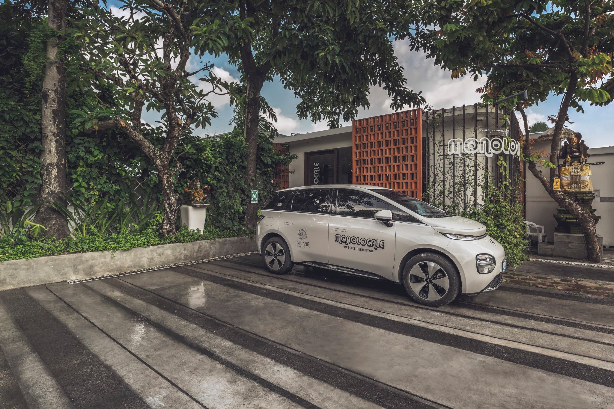 A white car parked on a wet road with a building in the background.