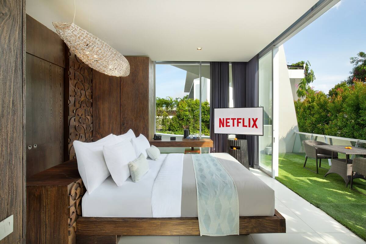 Moderni makuuhuone, jossa on suuri sänky, näkymä ulos ja kyltti, joka osoittaa Netflix-palvelun olevan saatavilla.