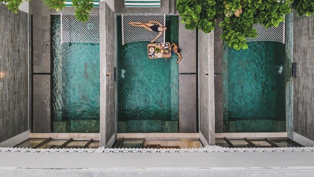 A modern pool area with clear water, surrounded by greenery and a wooden deck. - Monolocale Resort & Spa Seminyak by Ini Vie Hospitality (Keroboken Kelod)