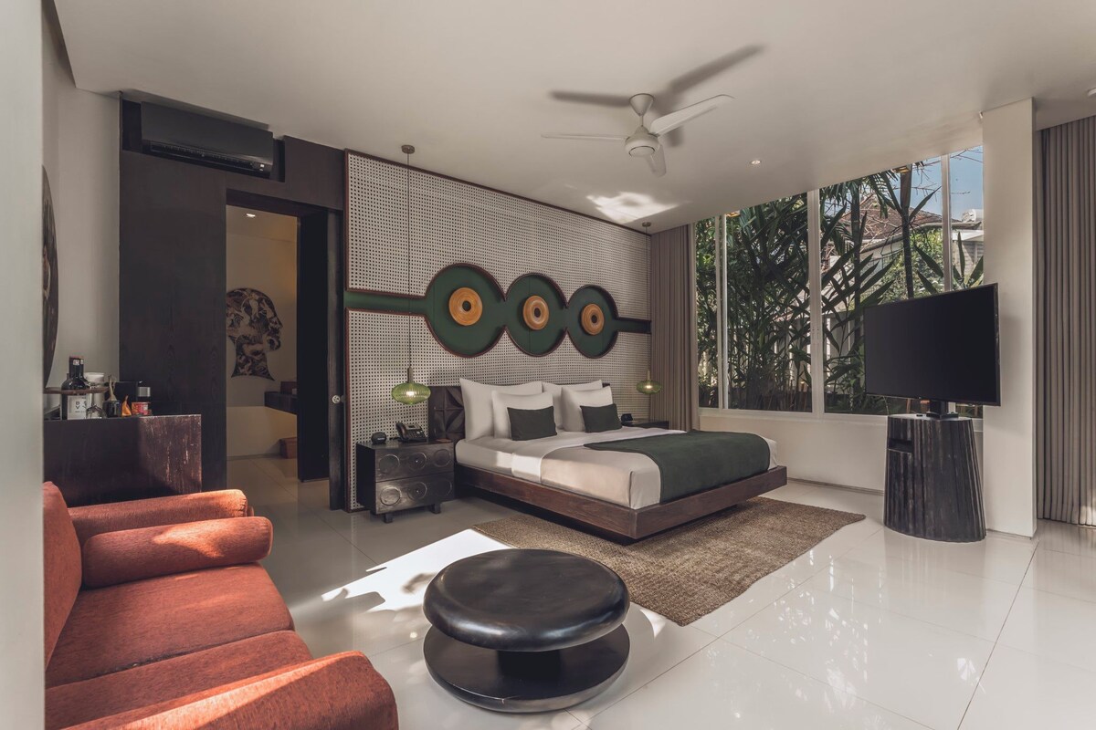 A modern bedroom with a bed, a TV, a ceiling fan, and a large window.