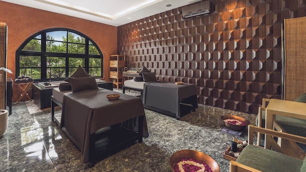 A modern room with a large arched window, a wall with a geometric pattern, and a seating area with a table and chairs. - Monolocale Resort & Spa Seminyak by Ini Vie Hospitality (Keroboken Kelod)