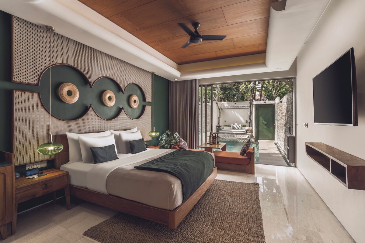 A modern bedroom with a bed, bedside tables, a TV, and a view of a pool.