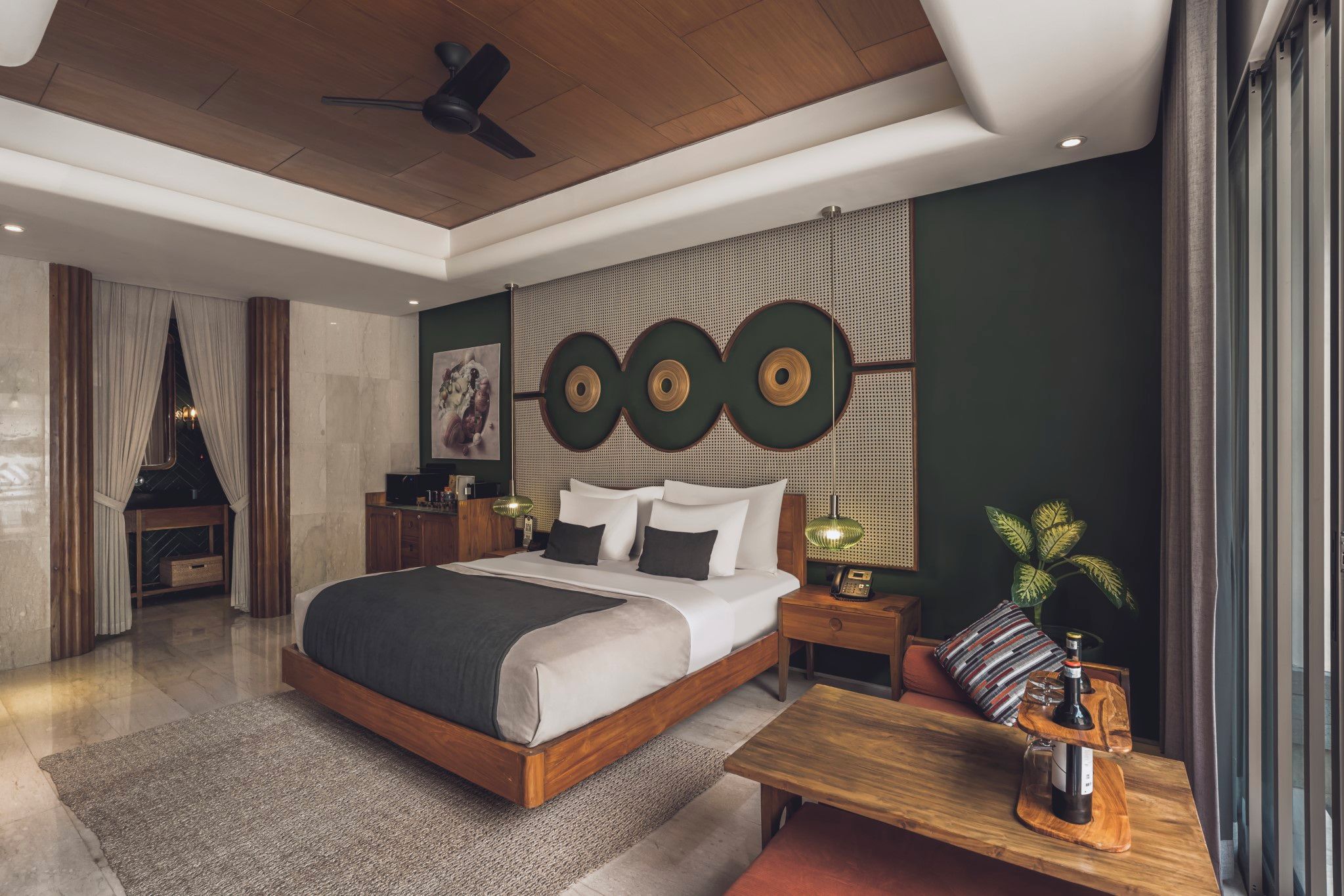 Quarto moderno com uma cama grande, mesas de cabeceira, cabeceira de madeira, ventilador de teto e uma obra de arte pendurada na parede.