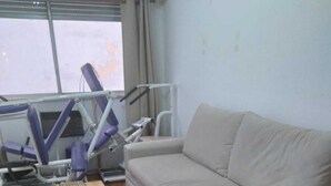 Una habitación con un sofá color beige, una mesa de centro de madera y equipo de ejercicio.