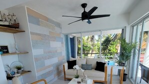 Un salon moderne comprenant un canapé, deux fauteuils, une table basse et un ventilateur de plafond.