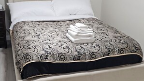 Un lit avec une couvre-lit à motifs, une tête de lit et une fenêtre avec des stores.