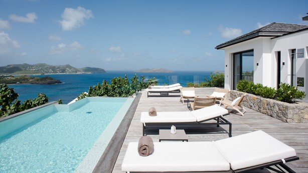 Una piscina infinita con sillones de descanso y vistas al mar.