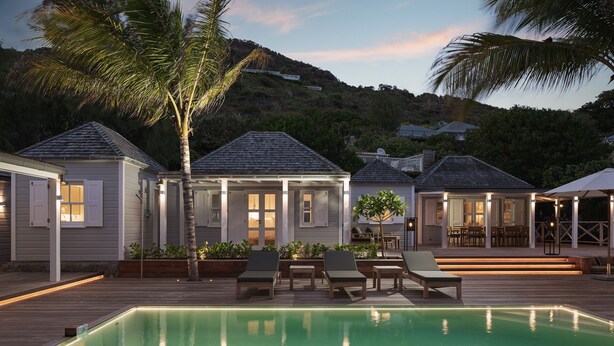 Ein Poolbereich mit Liegestühlen, einer Holzterrasse und einem Haus mit überdachter Veranda.