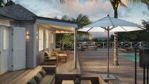 Une terrasse en bois avec des sièges extérieurs, une piscine et une vue sur l’océan.