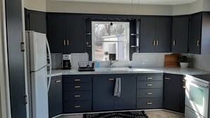 Una cocina moderna con armarios oscuros, un refrigerador blanco, una cafetera y un horno empotrado.