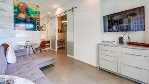 A modern living room with a sofa, a small table, and a TV mounted on the wall.