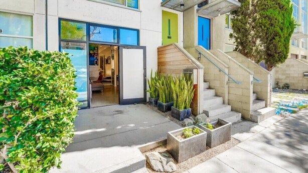 A modern building with a glass entrance, a staircase, and a well-maintained garden area.