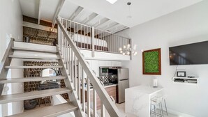 Eine moderne Küche mit Einbauofen und Mikrowelle, ein Essbereich mit Barhocker und eine Treppe mit Metallgeländer.