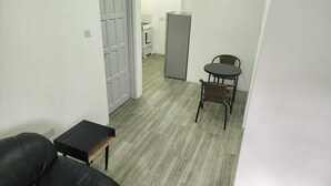 A compact living space with a sofa, a small table, a dining table with chairs, a refrigerator, and a washing machine. - Steps away from a beach & local transportation. Cozy one bedroom apartment (Saint George's)