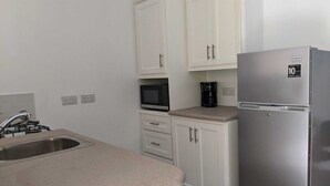 A kitchen with white cabinets, a stainless steel refrigerator, a microwave, and a coffee maker. - Steps away from a beach & local transportation. Cozy one bedroom apartment (Saint George's)
